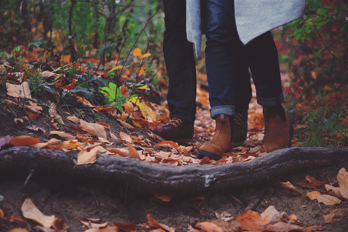 a woman walking through the woods in autumn